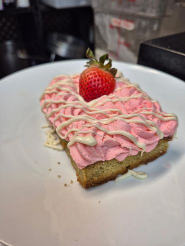 Slice of cake with strawberry and pink frosting.