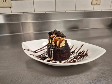 Chocolate lava cake with vanilla ice cream and chocolate drizzle.