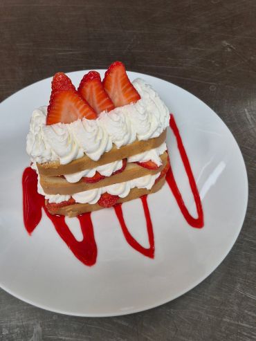 Strawberry and cream layered dessert with red syrup drizzle.