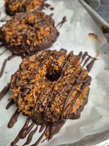 Chocolate drizzled coconut cookies on parchment.