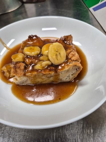 Banana bread soaked in syrup in a white bowl.
