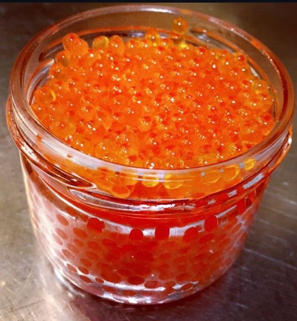 A glass jar filled with bright orange salmon roe.