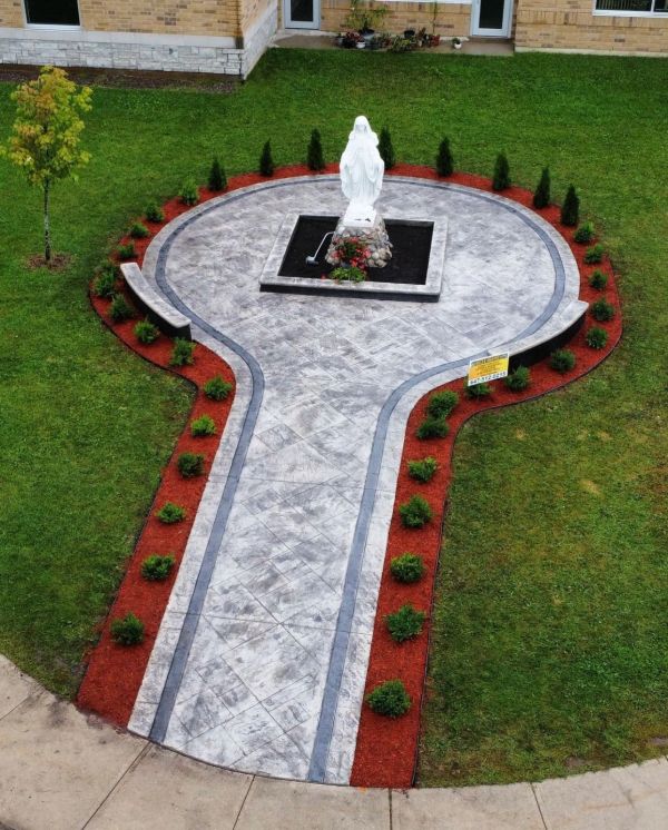 Pathway shaped like a key leading to a white statue in a garden.