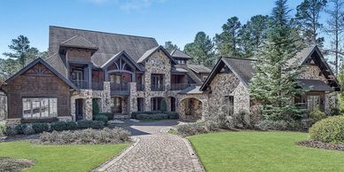 Large stone and wood luxury house with green lawn.
