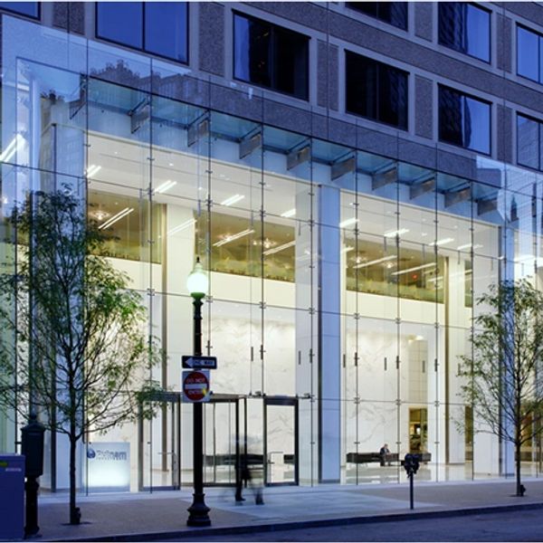 Modern glass building facade with illuminated interior at dusk.