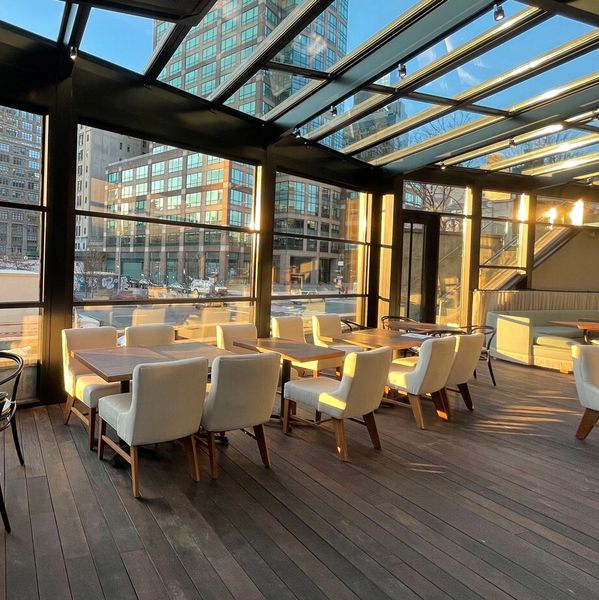 Sunlit modern dining area with glass walls and comfortable chairs.