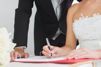 Bride and groom signing wedding documents with pens