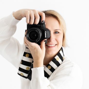 Femme souriante prenant une photo avec un appareil photo Canon.