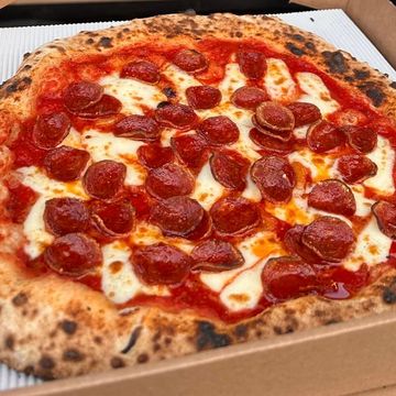 Pepperoni pizza with melted cheese in a cardboard box.