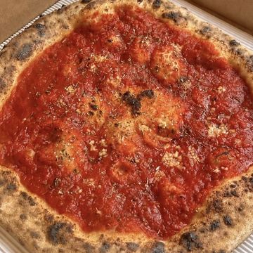 A rustic pizza topped with rich tomato sauce and herbs on a crispy crust.