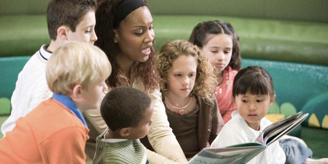 Teacher reading a book to a diverse group of children.