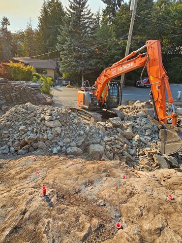 Orange Hitachi excavator working on rocky construction site at sunset.