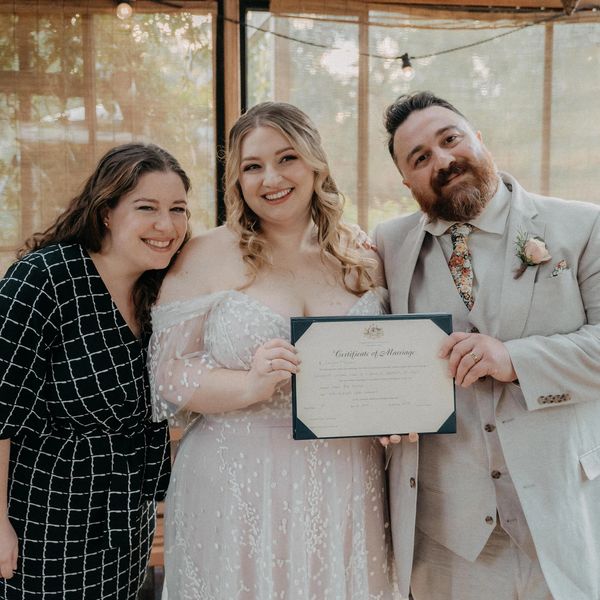 George the Celebrant, Hanna and Justin holding their signed marriage certificate after their ceremon