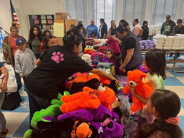 People selecting colorful stuffed animals and clothes at a community event.