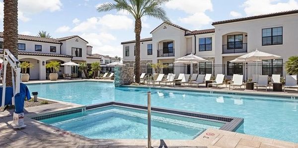 Modern resort pool with lounge chairs and umbrellas.