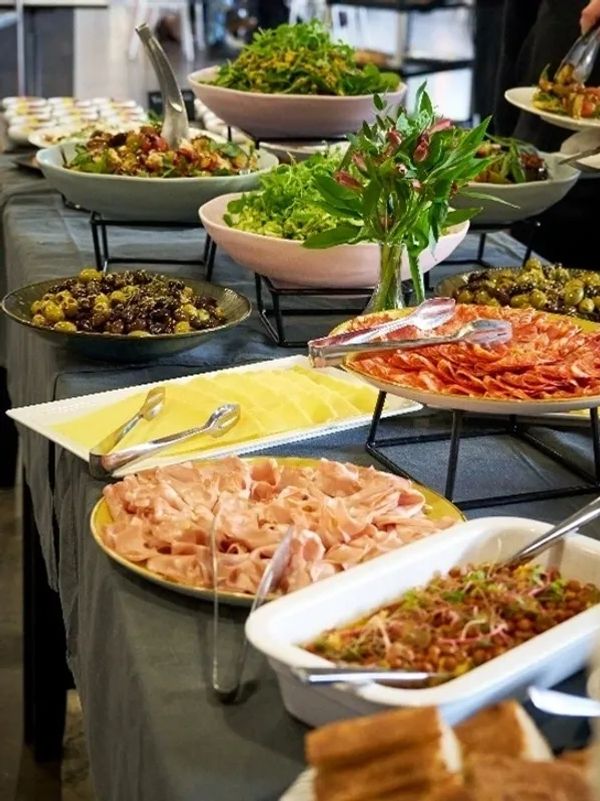 Buffet table with salads, olives, cold cuts, and cheese.