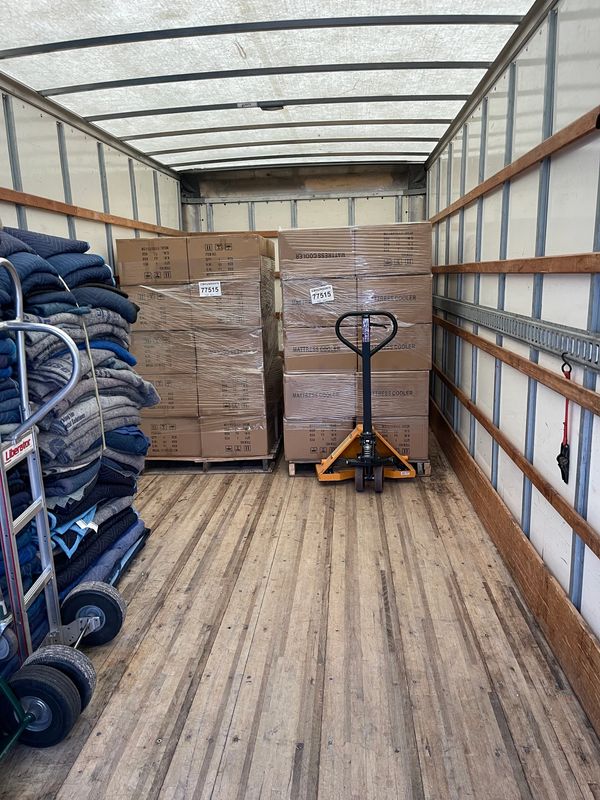 Inside a truck loaded with boxes, blankets, and a pallet jack.
