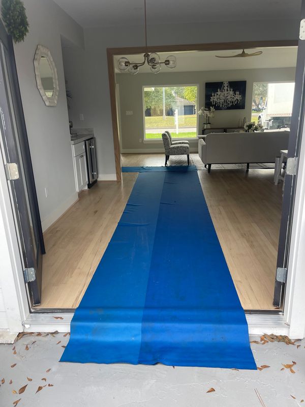 Blue protective floor covering leading into a modern living room.