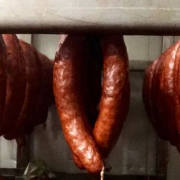 Foreman's Smoked Sausage still on the hanging rack fresh out of the smokehouse.