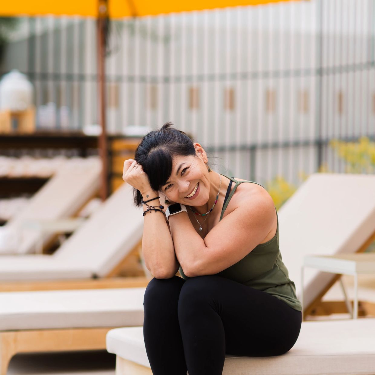 Private Yoga instructor Karen, smiling and sitting on a lounge chair outdoors.