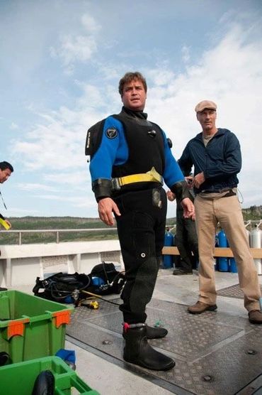 Bradley Williamson on deck in dry suit ready to dive for sunken treasure in cold water.