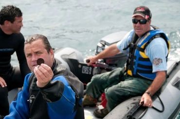 Bradley Williamson holding silver coin recovered from shipwreck in Canada.