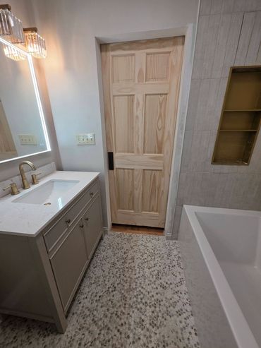 Modern bathroom with a wooden door and a bathtub.