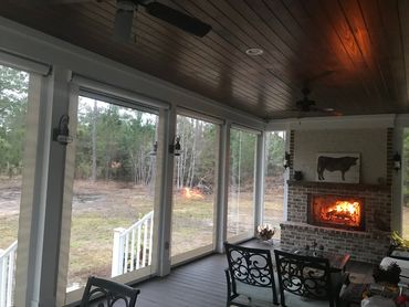 Cozy porch with fireplace and view of forest.