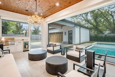 Modern outdoor living space with chandelier and pool view.