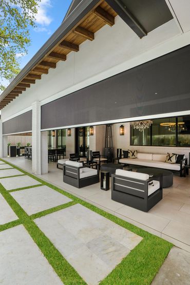 Modern outdoor lounge with black furniture and retractable shades.
