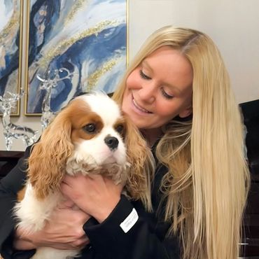 Woman lovingly holding a Cavalier Kong Charles Spaniel dog
