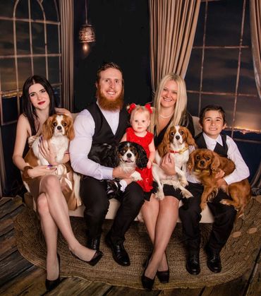 Family and Cavalier puppies posing for Christmas photo