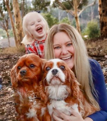 Mom and daughter laughing with Cavalier King Charles spaniel dogs