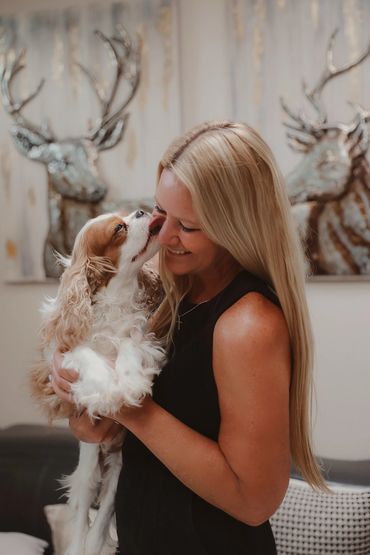 Cavalier dog licking smiling women in the face.