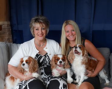 Grandmother and daughter holding three Cavalier Kong Charles Spaniel dogs