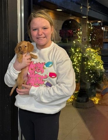 Young girl holding a small puppy and smiling.