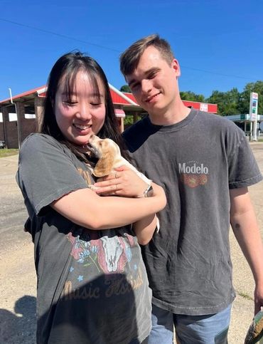 Young couple happily holding a small puppy outdoors.