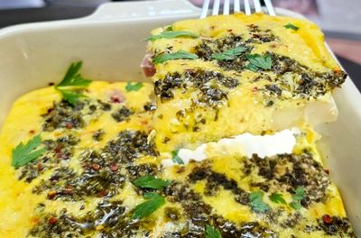 A slice of herb-topped baked casserole with creamy layers being served.