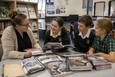 Teacher and students engaging in a lively book discussion in a library.