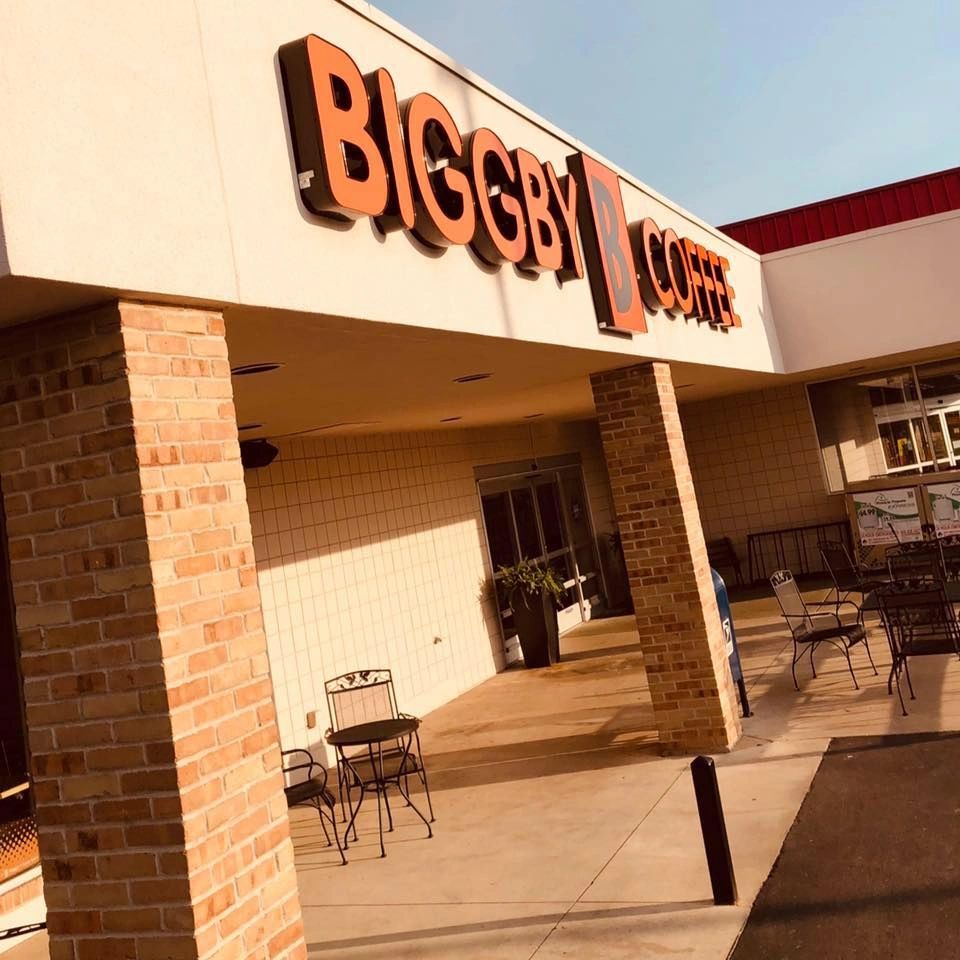 Outdoor seating area at Biggby Coffee with brick pillars and bright signage.