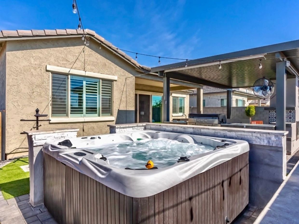 Outdoor hot tub with bubbling water in a sunny backyard patio.