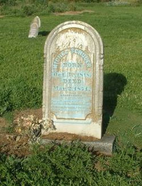 Old weathered gravestone in a grassy cemetery.