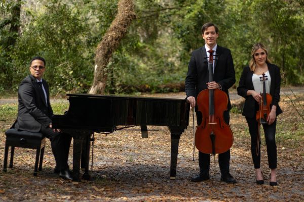 Three musicians posing outdoors with their instruments.