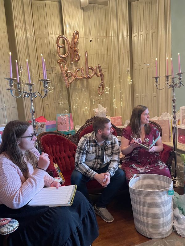 A group of family members opening baby shower gifts.