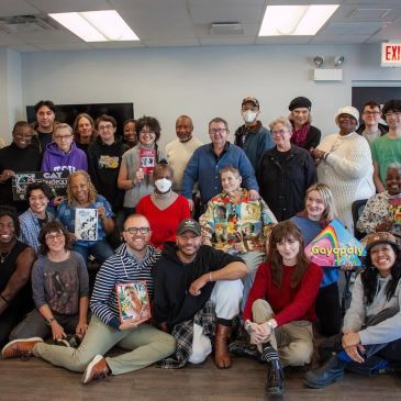 A diverse group of people smiling together indoors in a community setting.