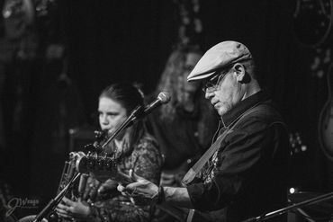 Black and white photo of musicians playing saxophone and guitar on stage.