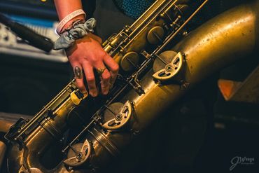 Close-up of a hand playing a vintage saxophone with detailed keys.