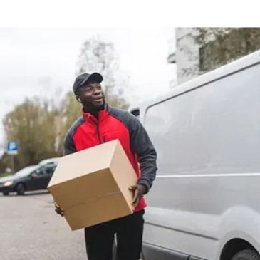 Delivery man carrying a cardboard box near a white van.