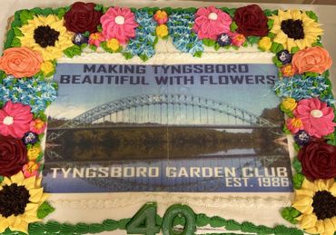 A decorated cake celebrating Tyngsboro Garden Club's 40th anniversary with floral icing and bridge image.