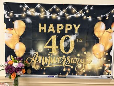 Decorative banner celebrating a 40th anniversary with gold balloons and lights.